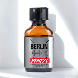 Set against a minimalist white background, the sleek amber glass bottle with a black cap bears the label "Berlin Hard Pentyl 24ml," poppers