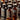 Rows of dark amber bottles labeled PENTYL and LIQUID GOLD are elegantly arranged on a reflective surface. With black caps and stylish text, they present a sleek uniform look. Under warm lighting, the glossy effect hints at exploring how many types of poppers exist in this collection.